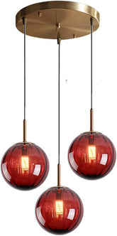 Modern pendant light with three red glass shades and gold accents on a white background